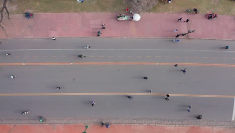 Aerial-vertical-top-view-of-crowds-of-people-doing-sports-on-a-pedestrian-road-with-bike-lane