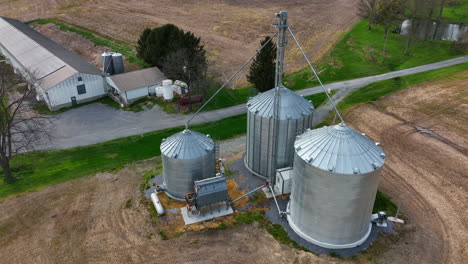 Grain-bins-for-corn-storage-on-family-farm-with-agriculture-barn-and-chicken-pig-house-in-view