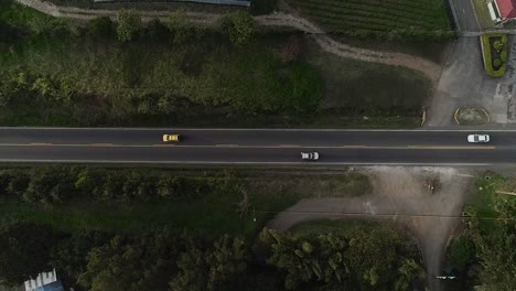 Overhead-aerial-drone-shot:-the-traffic-on-a-lane-surrounded-by-nature-in-the-city-outskirts