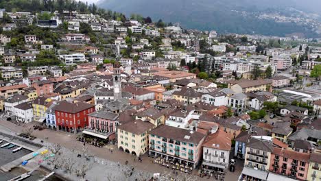 Luftüberführung-Mit-Einer-Drehung-Vom-Lago-Maggiore-über-Die-Promenade-Von-Ascona-Im-Tessin,-Schweiz-über-Die-Dächer-Rund-Um-Den-Kirchturm,-Der-Den-See-Und-Die-Berge-Freigibt