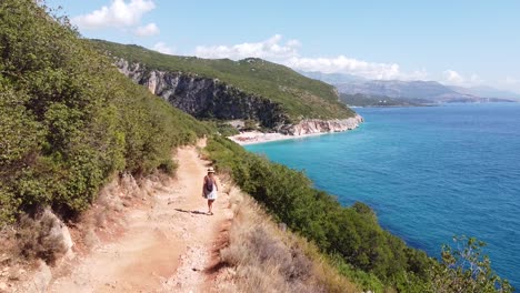 Chica-Turista-Camina-A-La-Hermosa-Playa-De-Gjipe-En-Albania---Seguimiento-De-Dolly-Aéreo