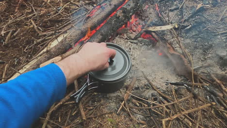 Steaming-hot-pasta-noodles-cooking-on-campfire-coals-covered-with-lid