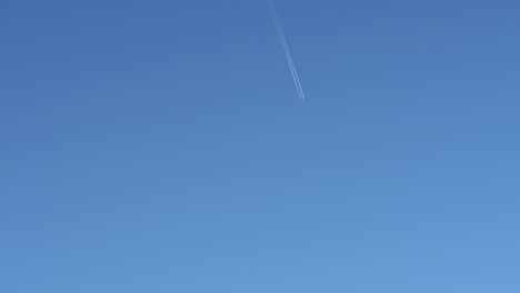 Plane-in-the-distance-in-an-open-cloudless-sky-leaving-a-trail-of-white-smoke