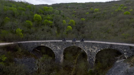 Three-Quad-Bikes-Driving-Through-An-Old-Bridge-In-Central-Istria,-Croatia,-Europe-During-The-Day