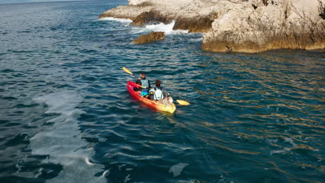 Dos-Amigos-Remando-Un-Kayak-Cerca-De-Los-Acantilados-En-Pula,-Istria,-Croacia---Toma-Aérea