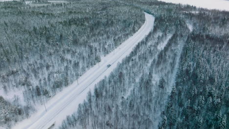 Aerial-View-Of-Vehicle-Driving-Through-Snowy-Roads-In-Lapland,-Finland---drone-shot