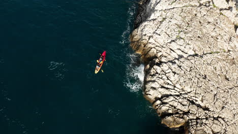 Turistas-En-Kayak-Junto-A-La-Costa-Pedregosa-Cerca-De-Pula-Istria,-Croacia-En-Europa-Durante-Un-Día-Soleado