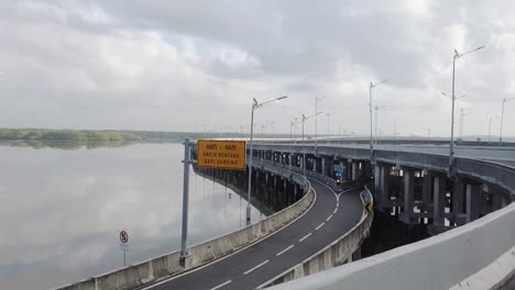 View-of-an-empty-highway-toll-bridges-over-a-river-with-white-clouds-passing-by-at-daytime