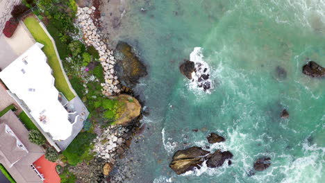 Waves-breaking-on-Californian-rocks-next-to-stunning-real-estate