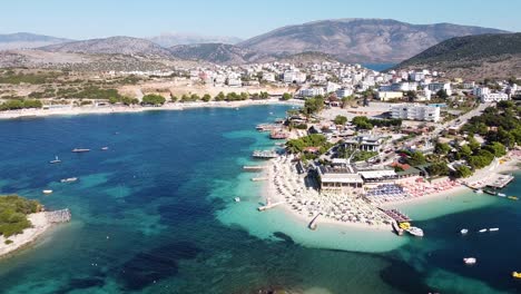 Ksamil,-Albania---Aerial-of-Holiday-Destination-with-Beach,-Sea,-Hotels,-Sunbeds,-Boats-and-Jetski