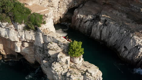 Tourists-Kayaking-Near-The-Cliffs-And-Caves-Of-Pula-Istria,-Croatia-In-Europe