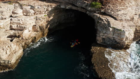 People-Kayaking-In-Caves-Near-Pula,-Istria,-Croatia---aerial-drone-shot
