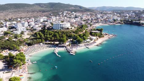 Ksamil,-Albania---Antena-De-Un-Popular-Destino-De-Vacaciones-Con-Hoteles,-Playa,-Tumbonas,-Mar-Iónico-E-Isla