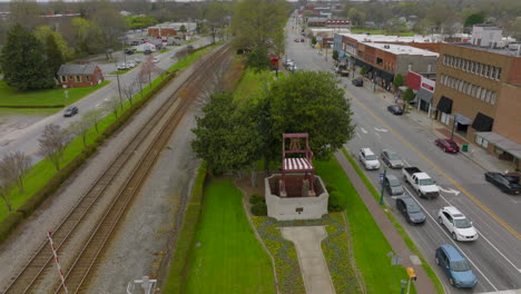 Aerial-of-big-chair-and-train-tracks-on-main-street-in-Thomasville,-North-Carolina-on-a-gray-Spring-day-with-a-tilt-up