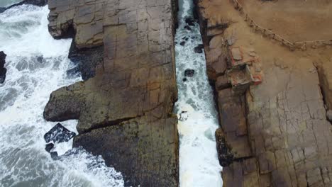 Top-down-drone-video-of-a-crevasse-on-a-rocky-outcrop-on-the-beach