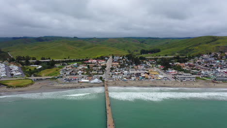 look-back-drone-shot-of-the-Californian-coast-line-with-a-jetty-in-the-center-of-the-shot