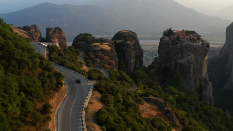 Car-On-Road-In-Mountains-Of-Meteora-In-Greece---aerial-drone-shot