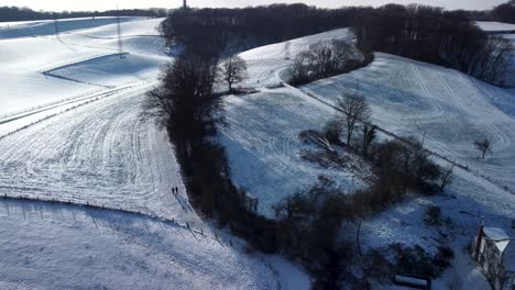 Two-walkers-enjoying-beautiful-winter-scenery-of-snowy-landscape---aerial-drone-descending