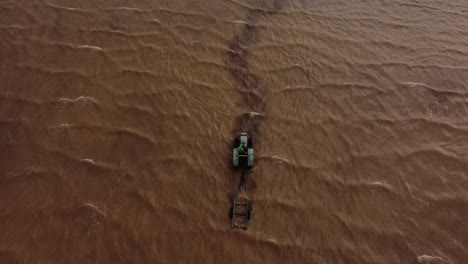 Aerial-top-down-of-tractor-entering-river-and-towing-boat-out-after-broke-down