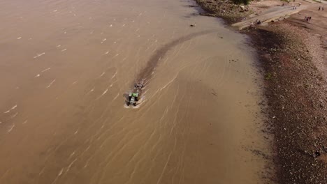 Aerial-view-of-tractor-entering-water-to-take-out-boat-of-River-Plate-in-Buenos-Aires,Argentina