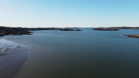 Drone-looking-over-Hingham-Harbour-with-birds-flying-around-on-a-calm-sunny-day