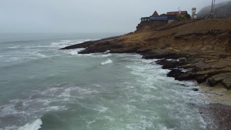 Drone-video-of-a-rocky-beach-shore-flying-towards-a-rocky-outcrop-on-a-foggy-day