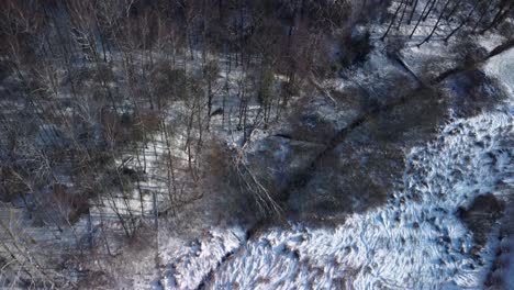 Drone-flyover-desolate-forest-during-cold-winter,-snow-covered-landin-Germany,-Europe