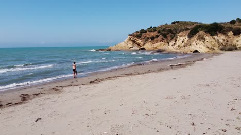 Woman-Walks-at-Sandy-Porto-Novo-Beach-in-Zvernec,-Vlore,-Albania---Slider