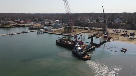 Semi-circle-aerial-footage-of-barge-and-tugboat-off-shore-of-harbor