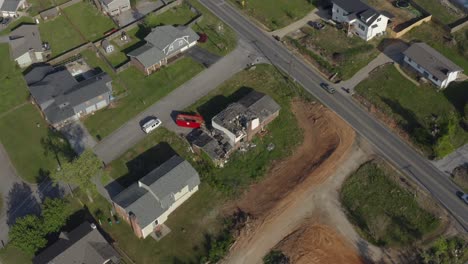 Drone-orbit-shot-aerial-of-a-storm-damaged-house-with-cars-casually-driving-by,-suburban-america