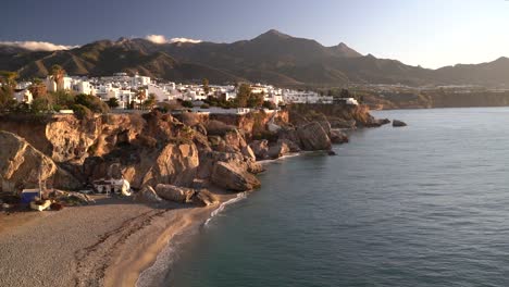 Stunning-view-towards-white-villas-on-cliffs-next-to-ocean-during-early-morning-hours