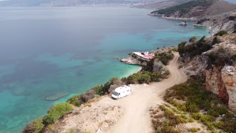 Vanlife-in-Ksamil,-Albania---Aerial-of-Camper-Van-at-Pulebardha-Beach,-with-Beautiful-View-of-White-Beach-and-Crystal-Blue-Sea