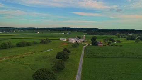 Eine-Luftaufnahme-Von-Maisfeldern-Und-Fruchtbarem-Ackerland-Und-Bauernhöfen-Während-Der-Goldenen-Stunde-An-Einem-Sonnigen-Sommertag