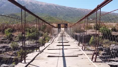 Wooden-and-Wobbly-Suspension-Bridge-across-Vjosa-River,-Albania---Fly-trough