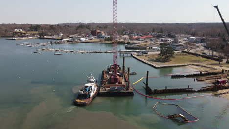 Aerial-static-shot-of-a-tug-boat-and-barge-with-crane-in-harbor