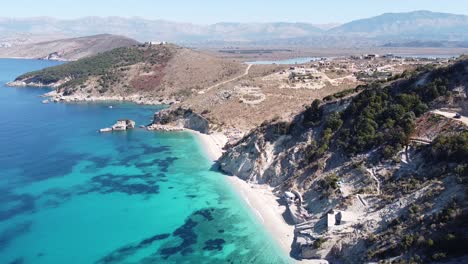 Ksamil,-Albania---Antena-De-La-Costa-Con-Mar-Jónico-Azul-Claro,-Playas-Blancas-Y-Montañas