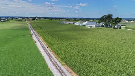 An-Aerial-180-Degree-View-of-Rich-Farmlands-and-Corn-Fields-Along-a-Single-Railroad-Track-on-a-Sunny-Summer-Day