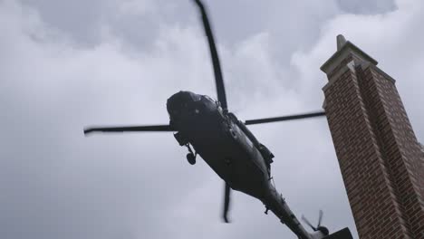 Slow-motion-shot-of-blackhawk-helicopter-flying-over-a-building-in-the-sky