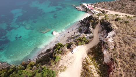 Vanlife-in-Ksamil,-Albania---Aerial-of-Motorhome-at-Pulebardha-Beach,-with-Beautiful-View-of-White-Beach-and-Crystal-Blue-Sea