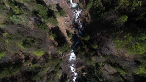 Vista-De-Arriba-Hacia-Abajo-De-Un-Dron-Del-Río-En-Un-Desfiladero-Profundo-Y-Una-Cascada-En-Suiza