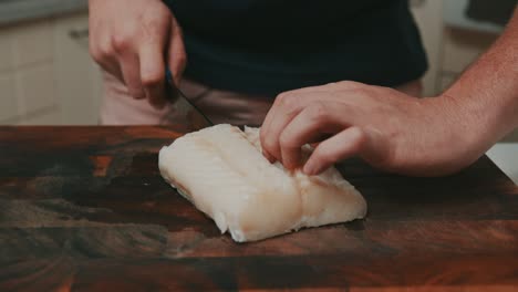 Slicing-white-fish-meat-on-wooden-cutting-board