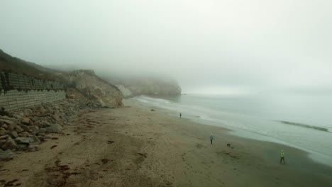 Gente-Caminando-En-La-Playa-En-Un-Día-De-Niebla