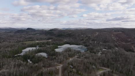 Drone-Flying-Towards-The-Frozen-Lake-With-Cloudy-Sky-In-Mont-Tremblant-National-Park,-Quebec,-Canada