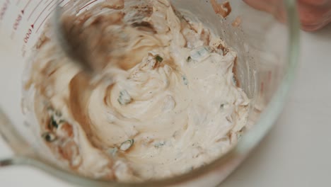 Mixing-vegetable-sauce-ingredients-with-mayonnaise-inside-measure-glass-bowl