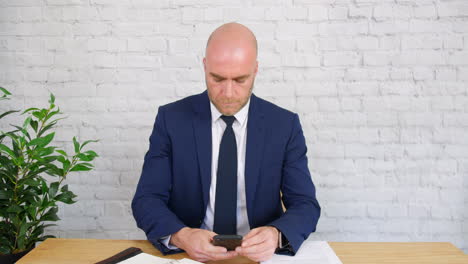 A-bored-businessman-checks-his-phone-at-work