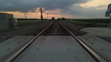Drone-Shot-Tracking-Low-Just-Above-Railroad-Tracks-After-Sunset-In-Texas,-U