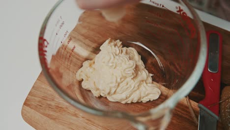 Squeezing-mayonnaise-into-glass-measure-bowl