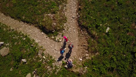 Family-hiking-in-the-swiss-alps,-top-view-by-drone