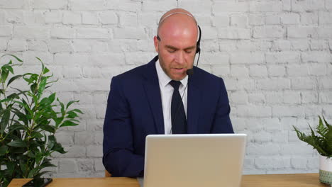 A-businessman-giving-customer-support-using-a-headset-and-laptop-computer