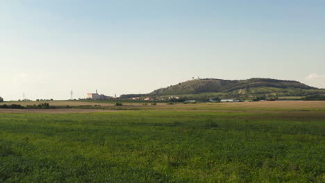 Fields-below-Svatý-Kopeček-hill-in-Moravia-landscape,-dolly-drone-shot